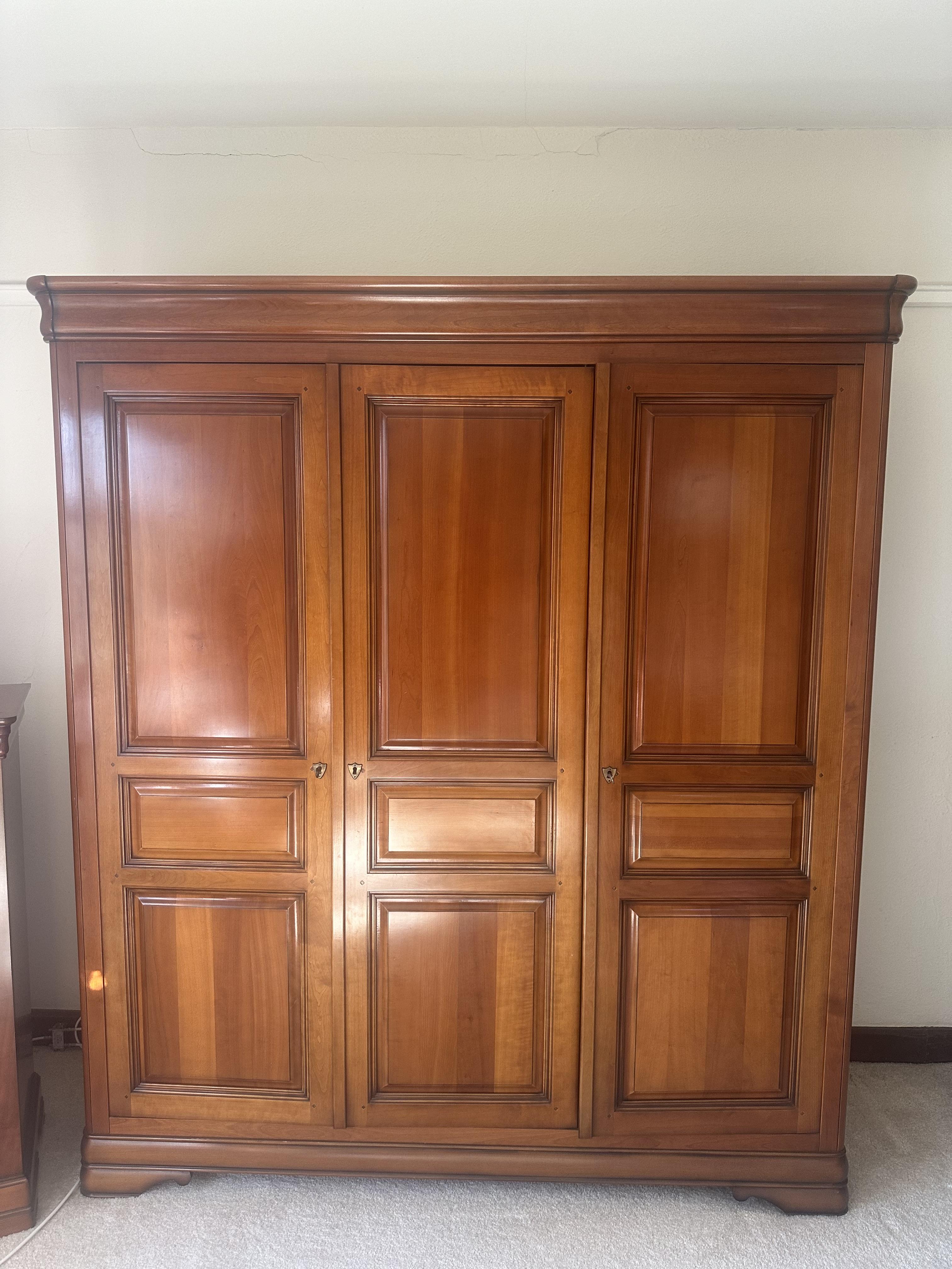 A French style cherry five piece bedroom suite, comprising triple wardrobe, four drawer chest, tall five drawer chest and a pair of bedside cabinets